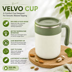 A VELVO CUP insulated travel mug with a light sage green lid and handle, shown on a wooden board with pistachios. The background is a soft, warm off-white with decorative green leaves, and the left side features a text panel detailing the mug's features: BPA free, better temperature retention, leak resistant lid, easy to clean, lightweight, and 200 ml capacity.