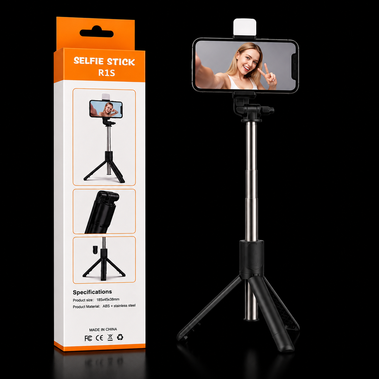 A black and silver selfie stick tripod shown next to its retail packaging box on a black background. The phone mounted on the stick displays a selfie photo.